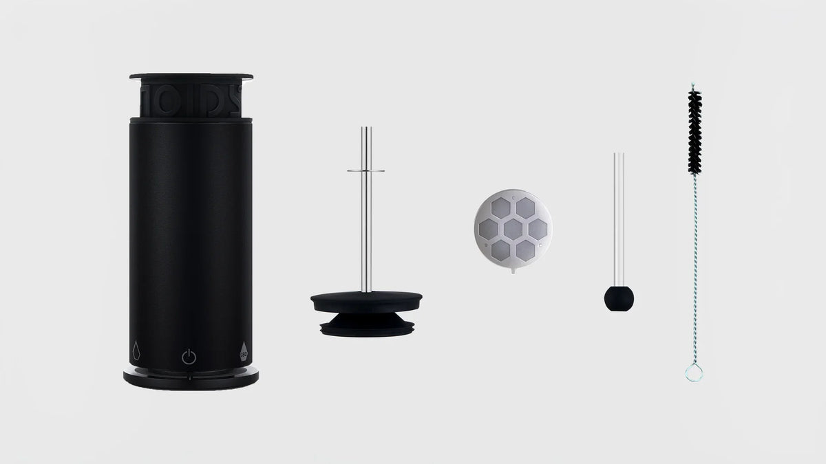 The NOIDS Herb Lab with its lid, filter, glass pipette and cleaning brush laid out on light grey